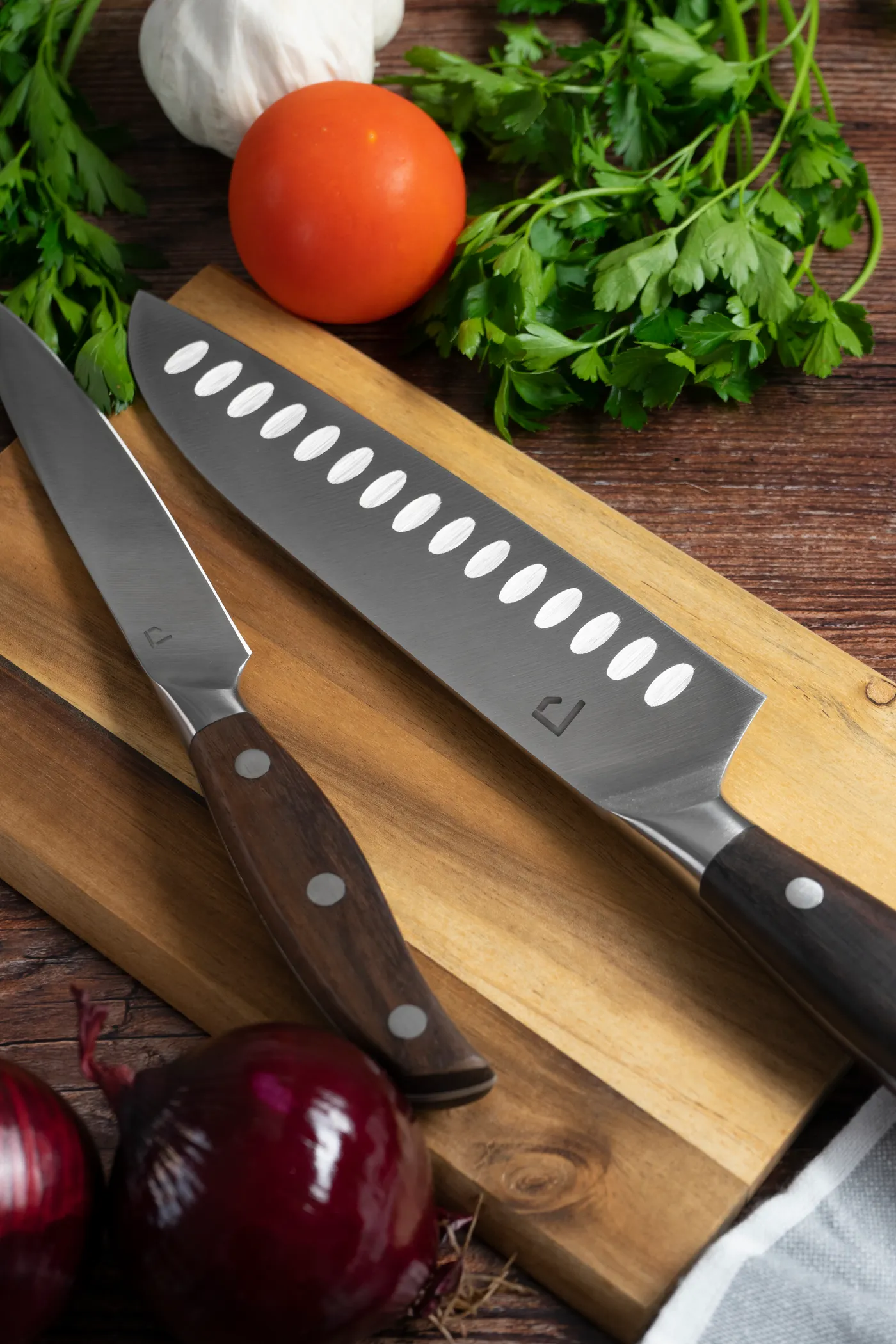 Two Patina knives on a board, the mark etched into the blade